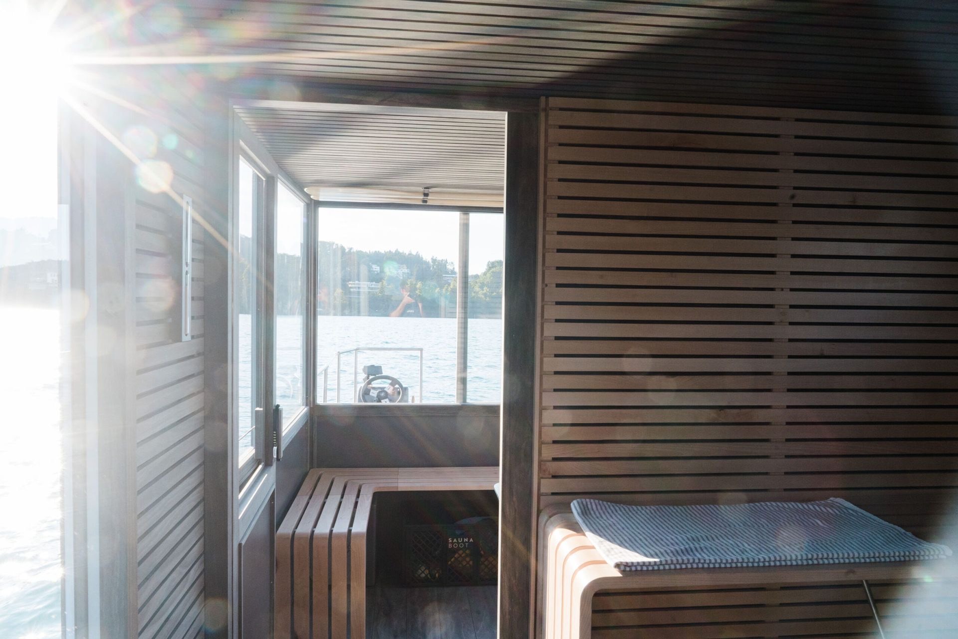 Interno in legno della sauna a bordo, con le vetrate sul lago